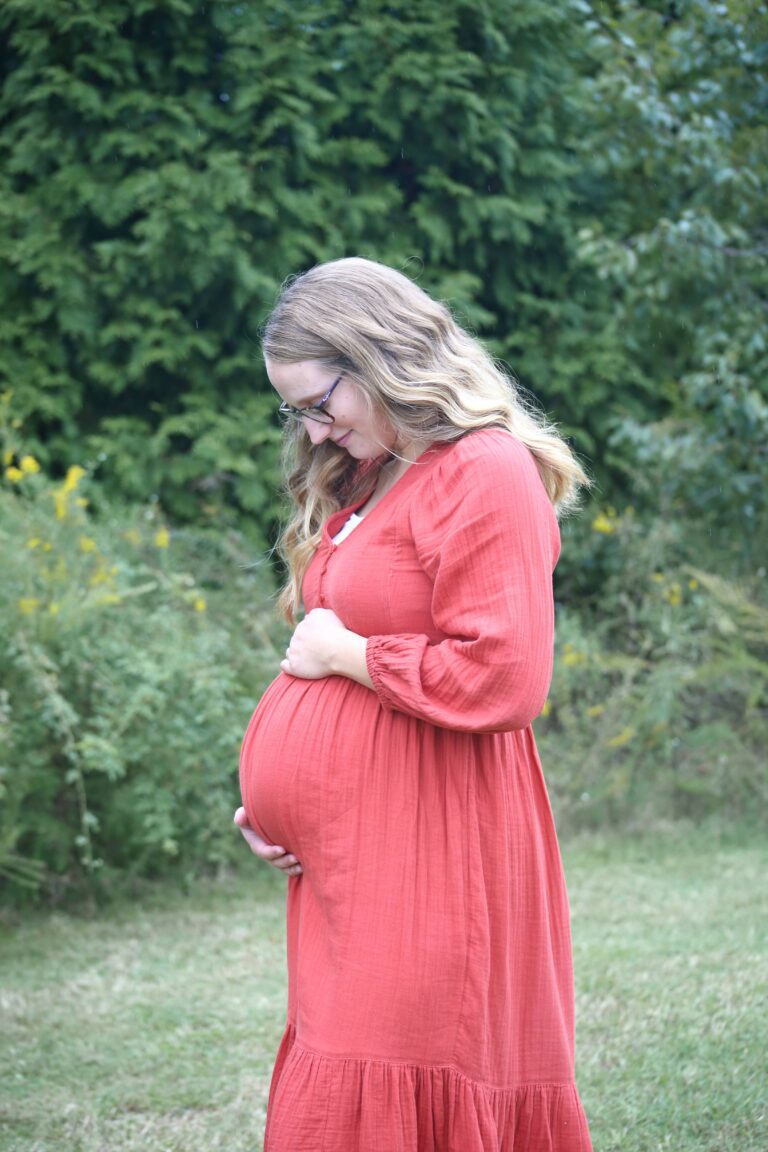 pregnant woman wearing orange dress in front of trees